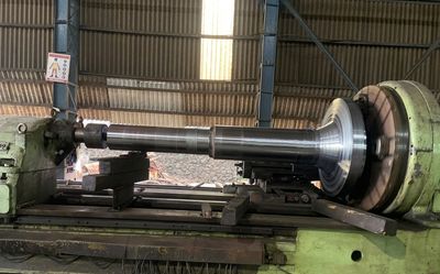 Machining shop floor — large shaft on horizontal lathe, 7,900 kg piece